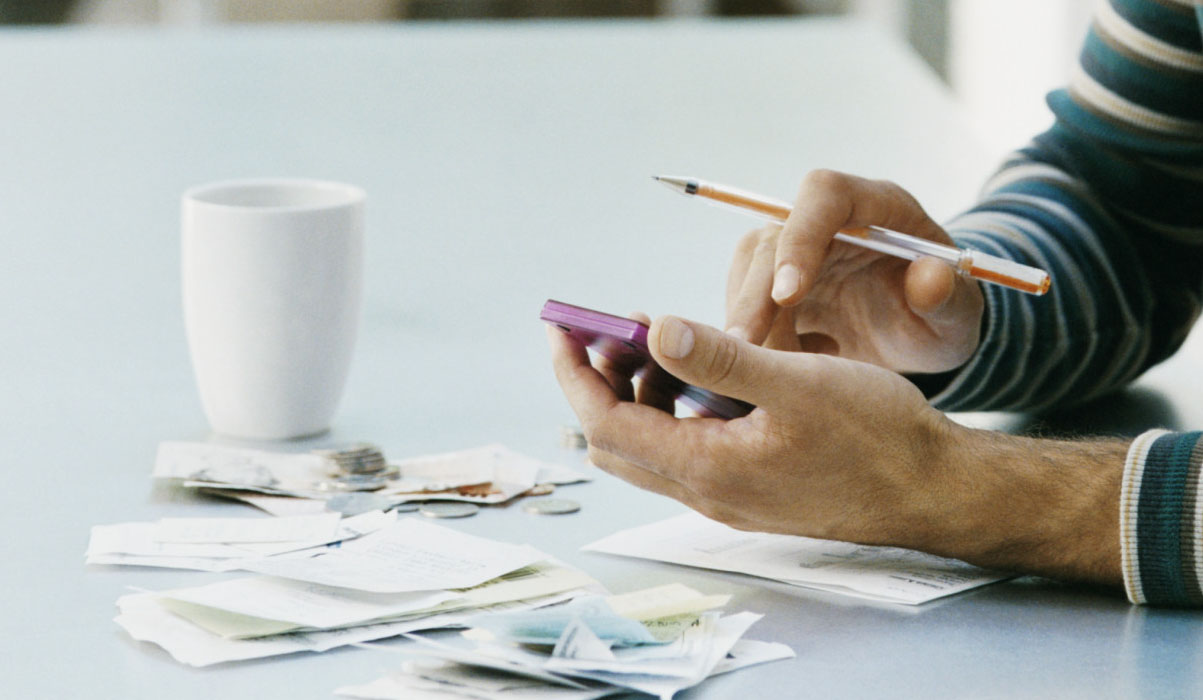 Man Sitting at a Table Using a Calculator